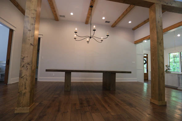 hardwood dining table dark brown in color in large room with columns no chairs