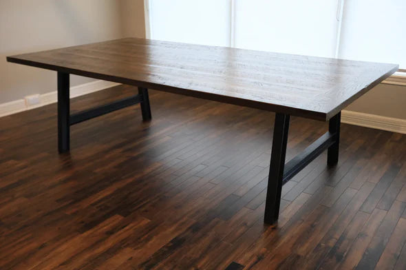 A Frame dining table dark top black metal legs bright window behind dark wood floors