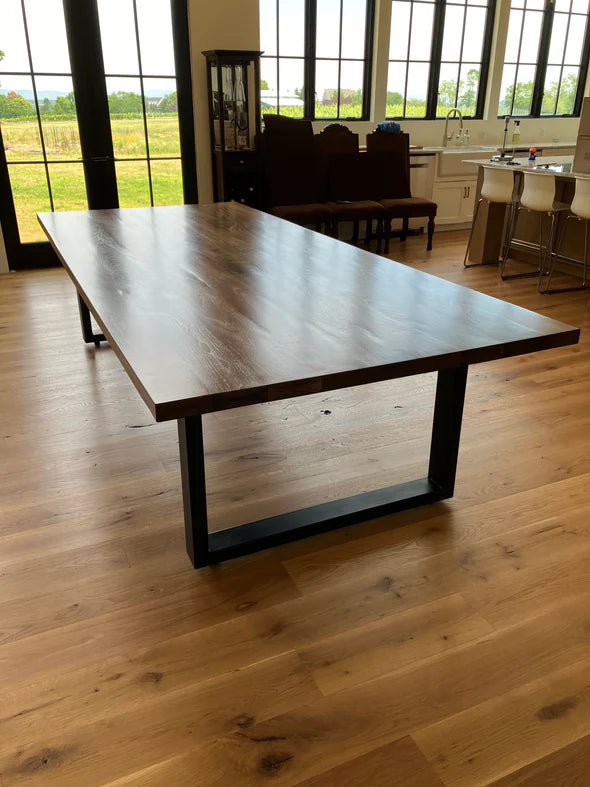 large modern dining table hardwood floor large windows behind with green field