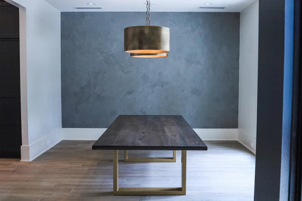 modern dining table dark top with gold legs green background gold lights above