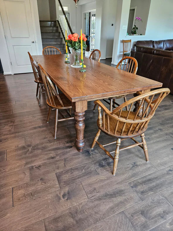 hardwood dining table light brown stain 6 matching chairs orange flowers and yellow candles in center piece