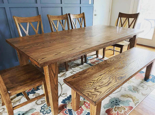 hardwood dining table with 5 chairs and a bench all stained brown on rug